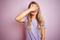 Young beautiful woman wearing purple t-shirt standing over pink isolated background smiling and laughing with hand on face Royalty Free Stock Photo