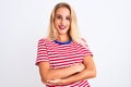 Young beautiful woman wearing red striped t-shirt standing over isolated white background happy face smiling with crossed arms Royalty Free Stock Photo