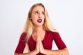 Young beautiful woman wearing red t-shirt standing over isolated white background begging and praying with hands together with Royalty Free Stock Photo