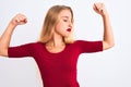 Young beautiful woman wearing red t-shirt standing over isolated white background showing arms muscles smiling proud Royalty Free Stock Photo