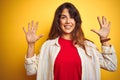 Young beautiful woman wearing red t-shirt and stripes shirt over yellow isolated background showing and pointing up with fingers