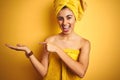 Young beautiful woman wearing a shower towel after bath over yellow isolated background amazed and smiling to the camera while Royalty Free Stock Photo