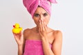 Young beautiful woman wearing shower towel holding duck over isolated white background cover mouth with hand shocked with shame Royalty Free Stock Photo