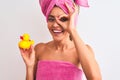 Young beautiful woman wearing shower towel holding duck over isolated white background with happy face smiling doing ok sign with Royalty Free Stock Photo