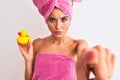 Young beautiful woman wearing shower towel holding duck over isolated white background pointing with finger to the camera and to Royalty Free Stock Photo