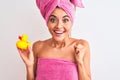 Young beautiful woman wearing shower towel holding duck over isolated white background screaming proud and celebrating victory and Royalty Free Stock Photo