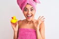 Young beautiful woman wearing shower towel holding duck over isolated white background very happy and excited, winner expression Royalty Free Stock Photo