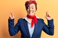 Young beautiful woman wearing stewardess uniform gesturing finger crossed smiling with hope and eyes closed