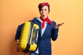 Young beautiful woman wearing stewardess uniform holding cabin bag scared and amazed with open mouth for surprise, disbelief face