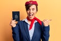 Young beautiful woman wearing stewardess uniform holding canadian passport pointing thumb up to the side smiling happy with open