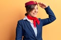 Young beautiful woman wearing stewardess uniform very happy and smiling looking far away with hand over head