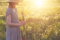 Beautiful woman wearing straw hat and long linen dress enjoying nature, holding bouquet of fresh beautiful wildflowers and green g Royalty Free Stock Photo