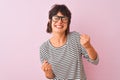 Young beautiful woman wearing striped t-shirt and glasses over isolated pink background very happy and excited doing winner Royalty Free Stock Photo