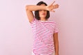 Young beautiful woman wearing striped t-shirt standing over isolated pink background covering eyes with arm, looking serious and Royalty Free Stock Photo