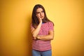 Young beautiful woman wearing striped t-shirt standing over isolated yellow background thinking looking tired and bored with Royalty Free Stock Photo