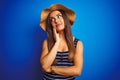Young beautiful woman wearing striped t-shirt and summer hat over isolated blue background with hand on chin thinking about Royalty Free Stock Photo
