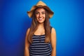 Young beautiful woman wearing striped t-shirt and summer hat over isolated blue background with a happy and cool smile on face Royalty Free Stock Photo