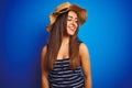 Young beautiful woman wearing striped t-shirt and summer hat over isolated blue background looking away to side with smile on Royalty Free Stock Photo