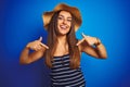 Young beautiful woman wearing striped t-shirt and summer hat over isolated blue background looking confident with smile on face, Royalty Free Stock Photo