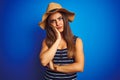 Young beautiful woman wearing striped t-shirt and summer hat over isolated blue background thinking looking tired and bored with Royalty Free Stock Photo