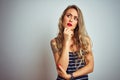 Young beautiful woman wearing stripes t-shirt standing over white isolated background with hand on chin thinking about question, Royalty Free Stock Photo