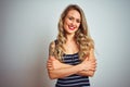 Young beautiful woman wearing stripes t-shirt standing over white isolated background happy face smiling with crossed arms looking Royalty Free Stock Photo