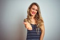 Young beautiful woman wearing stripes t-shirt standing over white isolated background smiling friendly offering handshake as Royalty Free Stock Photo