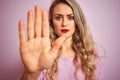 Young beautiful woman wearing sweater standing over pink isolated background with open hand doing stop sign with serious and Royalty Free Stock Photo