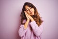 Young beautiful woman wearing sweater standing over pink isolated background sleeping tired dreaming and posing with hands Royalty Free Stock Photo