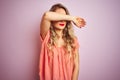 Young beautiful woman wearing t-shirt standing over pink isolated background covering eyes with arm, looking serious and sad Royalty Free Stock Photo