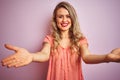 Young beautiful woman wearing t-shirt standing over pink isolated background looking at the camera smiling with open arms for hug Royalty Free Stock Photo