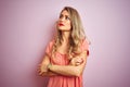 Young beautiful woman wearing t-shirt standing over pink isolated background looking to the side with arms crossed convinced and Royalty Free Stock Photo