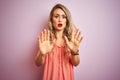 Young beautiful woman wearing t-shirt standing over pink isolated background Moving away hands palms showing refusal and denial Royalty Free Stock Photo