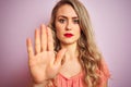 Young beautiful woman wearing t-shirt standing over pink isolated background with open hand doing stop sign with serious and Royalty Free Stock Photo