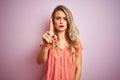 Young beautiful woman wearing t-shirt standing over pink isolated background Pointing with finger up and angry expression, showing Royalty Free Stock Photo