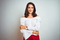 Young beautiful woman wearing t-shirt standing over white isolated background happy face smiling with crossed arms looking at the Royalty Free Stock Photo