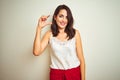 Young beautiful woman wearing t-shirt standing over white isolated background smiling and confident gesturing with hand doing Royalty Free Stock Photo