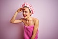 Young beautiful woman wearing towel and bath hat after shower over pink isolated background very happy and smiling looking far Royalty Free Stock Photo