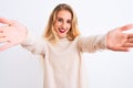 Young beautiful woman wearing turtleneck sweater standing over isolated white background looking at the camera smiling with open Royalty Free Stock Photo