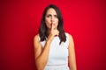 Young beautiful woman wearing white dress standing over red isolated background asking to be quiet with finger on lips Royalty Free Stock Photo