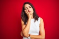 Young beautiful woman wearing white dress standing over red isolated background thinking looking tired and bored with depression Royalty Free Stock Photo