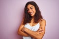 Young beautiful woman wearing white t-shirt standing over isolated pink background happy face smiling with crossed arms looking at Royalty Free Stock Photo