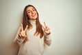 Young beautiful woman wearing winter turtleneck sweater over isolated white background smiling looking to the camera showing Royalty Free Stock Photo