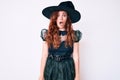 Young beautiful woman wearing witch halloween costume afraid and shocked with surprise and amazed expression, fear and excited