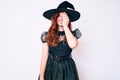 Young beautiful woman wearing witch halloween costume covering one eye with hand, confident smile on face and surprise emotion