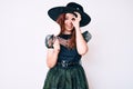 Young beautiful woman wearing witch halloween costume holding lollipop smiling happy doing ok sign with hand on eye looking Royalty Free Stock Photo