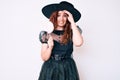 Young beautiful woman wearing witch halloween costume holding lollipop stressed and frustrated with hand on head, surprised and Royalty Free Stock Photo