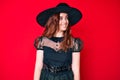 Young beautiful woman wearing witch halloween costume looking to side, relax profile pose with natural face and confident smile