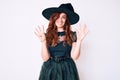 Young beautiful woman wearing witch halloween costume showing and pointing up with fingers number nine while smiling confident and