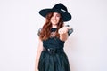 Young beautiful woman wearing witch halloween costume smiling cheerful offering palm hand giving assistance and acceptance